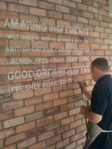 Wayne Osborne Signwriting a display wall sign